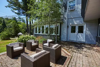a patio with chairs and tables in front of a house at 3 Pines Lodge Muskoka in Huntsville