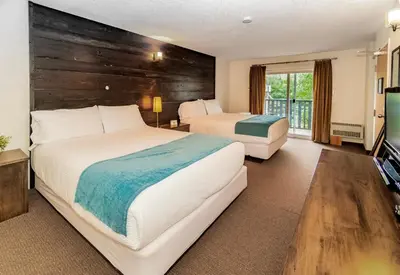 a hotel room with two beds and a television at 3 Pines Lodge Muskoka in Huntsville