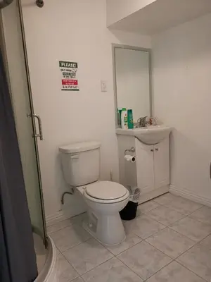 a bathroom with a toilet and a sink and a mirror at Private Rooms in House in North York Shared Kitchen in Toronto