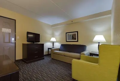 a hotel room with a couch and a tv at Country Inn & Suites by Radisson, Niagara Falls, ON in Niagara Falls