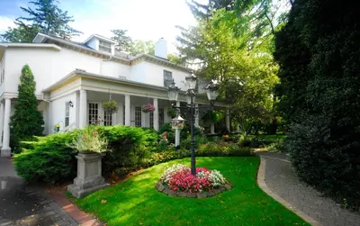 a white house with flowers in the yard at Brockamour Manor Bed and Breakfast in Niagara on the Lake