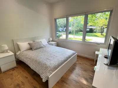 a bedroom with a bed and a large window at Stunning Modern Beach House with Swimming Pool and Spectacular Sunsets in Tiny