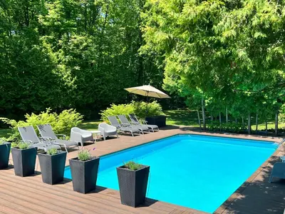 a swimming pool with lounge chairs and an umbrella at Stunning Modern Beach House with Swimming Pool and Spectacular Sunsets in Tiny