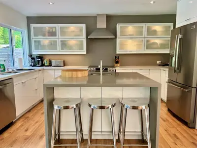 a kitchen with a large island with two bar stools at Stunning Modern Beach House with Swimming Pool and Spectacular Sunsets in Tiny
