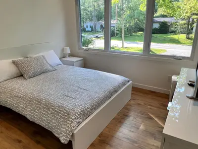 a bedroom with a bed and two windows at Stunning Modern Beach House with Swimming Pool and Spectacular Sunsets in Tiny