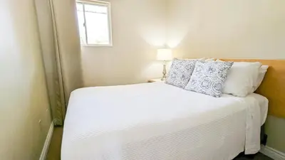 a bedroom with a white bed with pillows and a window at Oasis by the Bay Vacation Suites in Wasaga Beach