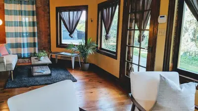 a living room with white chairs and windows at The Front Porch Room of a 140-Year-Old Victorian House in Orangeville