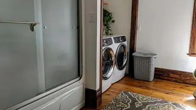 a washer and dryer in a room with a tv at The Front Porch Room of a 140-Year-Old Victorian House in Orangeville