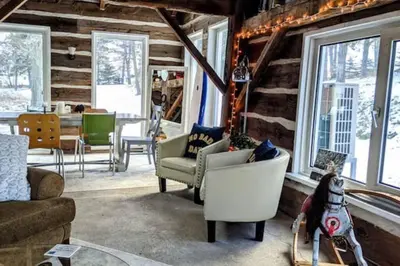 a living room with a couch and chairs and windows at A charming, rustic 150 year old Carriage House in Orangeville