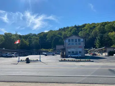 a building in a parking lot with cars parked at Silver Maple Motel in Haliburton