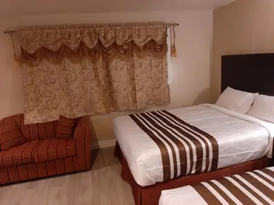 a hotel room with two beds and a chair at Silver Maple Motel in Haliburton