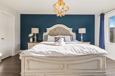 a bedroom with a white bed with a blue wall at Modern home with a pool sauna pooltable & mountain view in Collingwood