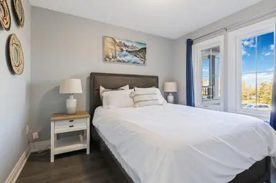 a bedroom with a white bed and a window at Modern home with a pool sauna pooltable & mountain view in Collingwood