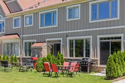 a house with chairs and a table and a grill at Modern home with a pool sauna pooltable & mountain view in Collingwood