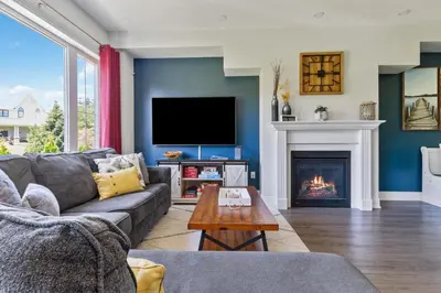 a living room with a couch and a fireplace at Modern home with a pool sauna pooltable & mountain view in Collingwood