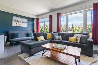 a living room with a couch and a table at Modern home with a pool sauna pooltable & mountain view in Collingwood