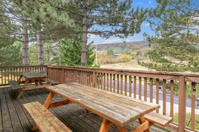 a wooden deck with a wooden picnic table on it at 12 Beds Sleep 16 Chalet with HotTub, 2min to Blue in Blue Mountains