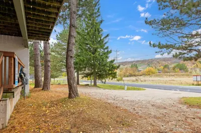 a porch of a house with trees next to a road at 12 Beds Sleep 16 Chalet with HotTub, 2min to Blue in Blue Mountains