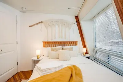 a bedroom with a large white bed and a window at The Beehive w Hot Tub Sauna & Fireplace in Blue Mountains