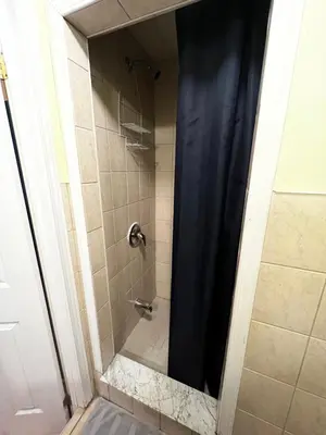 a shower with a blue shower curtain in a bathroom at Adas Guesthouse in Toronto