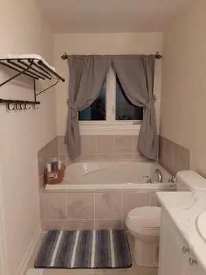a bathroom with a tub and a toilet and a window at Close Property in Bowmanville