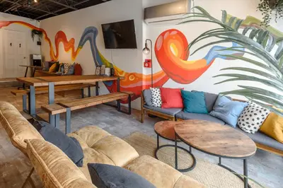a living room with couches and tables and a mural at Samesun Toronto in Toronto