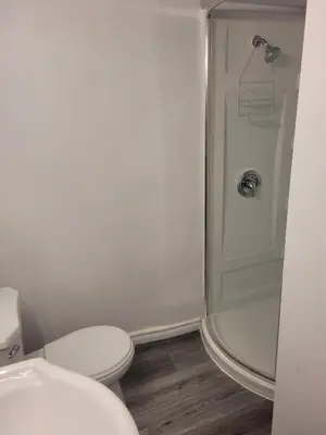 a white bathroom with a toilet and a shower at Adorable Studio Basement Suite in South Barrie in Barrie