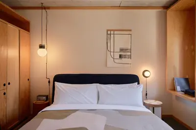a bedroom with a bed with white sheets and lamps at Ace Hotel Toronto in Toronto