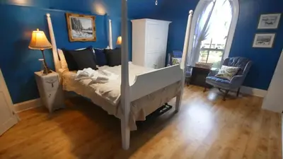 a bedroom with a bed and a blue wall at Bristows Inn in Elmira