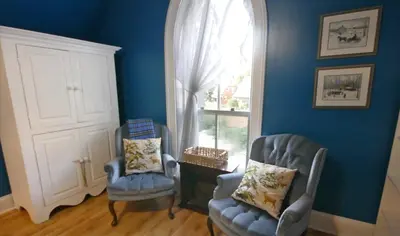 a blue room with two chairs and a window at Bristows Inn in Elmira