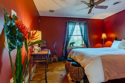 a bedroom with red walls and a bed with a plant at Emilyville Inn in Campbellford