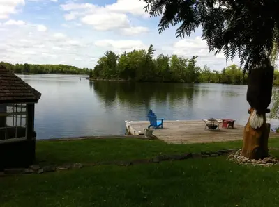 a blue chair sitting on a dock next to a lake at Windswept on the Trent in Campbellford