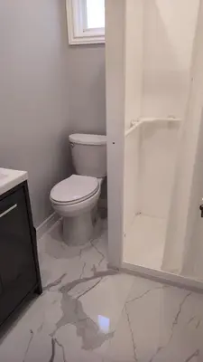 a white bathroom with a toilet and a shower at Wasaga Beach Cottage 2 in Wasaga Beach