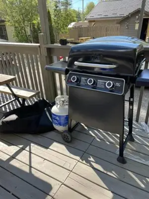 a grill on a deck with a table and a bench at Wasaga Beach Loft 4 in Wasaga Beach