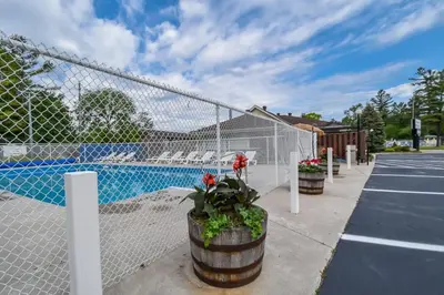 a fence next to a parking lot with a pool at Beach Club by Beach1 Motel in Wasaga Beach