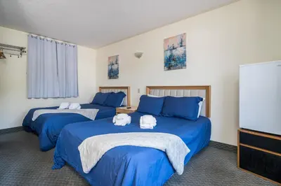 two beds in a room with blue sheets at Beach Club by Beach1 Motel in Wasaga Beach
