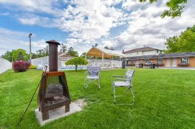 a yard with two chairs and a grill at Beach Club by Beach1 Motel in Wasaga Beach