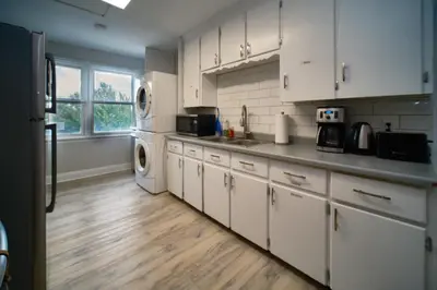 a kitchen with white cabinets and a wooden floor at Hamilton Chic Retreat - Comfy Beds - Garden - Pool in Hamilton