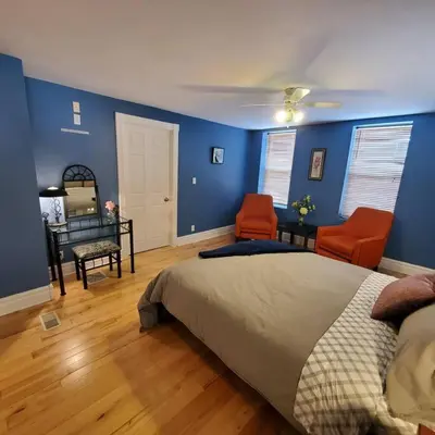 a bedroom with blue walls and a bed and two chairs at Garden 2 Storey House in Niagara Falls