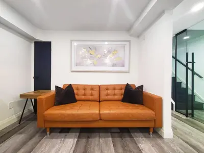 an orange couch in a room with a painting on the wall at Renovated Guest Suite Near The Lake & High Park in Toronto! in Toronto