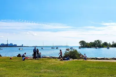 a group of people sitting on the grass near the water at Renovated Guest Suite Near The Lake & High Park in Toronto! in Toronto