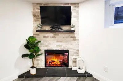 a living room with a fireplace with a flat screen tv at Renovated Guest Suite Near The Lake & High Park in Toronto! in Toronto