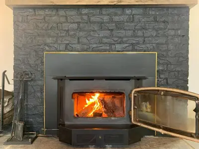 a stone fireplace with a fire in it at The Prince Edward County Church, A Unique Escape in Belleville