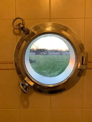 a round mirror on a wall in a bathroom at The Prince Edward County Church, A Unique Escape in Belleville