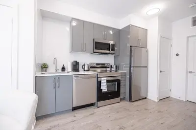 a kitchen with stainless steel appliances and white cabinets at Luxury & Comfy Apartment, Mins Drive To All Niagara Falls Attraction in Niagara Falls