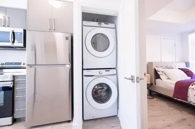 a kitchen with a refrigerator and a washer and dryer at Luxury & Comfy Apartment, Mins Drive To All Niagara Falls Attraction in Niagara Falls