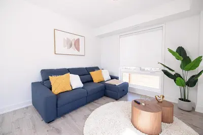 a living room with a blue couch and a table at Luxury & Comfy Apartment, Mins Drive To All Niagara Falls Attraction in Niagara Falls