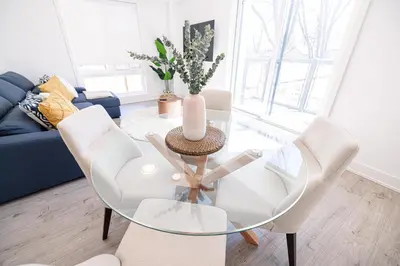 a living room with a glass table and chairs at Luxury & Comfy Apartment, Mins Drive To All Niagara Falls Attraction in Niagara Falls