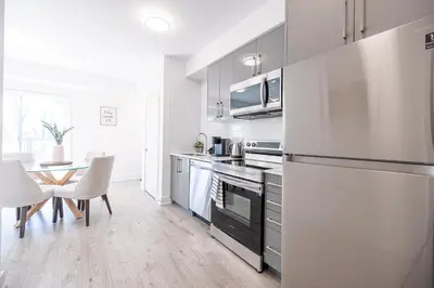 a kitchen with a refrigerator and a table with chairs at Luxury & Comfy Apartment, Mins Drive To All Niagara Falls Attraction in Niagara Falls