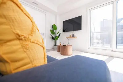 a living room with a bed and a tv at Luxury & Comfy Apartment, Mins Drive To All Niagara Falls Attraction in Niagara Falls